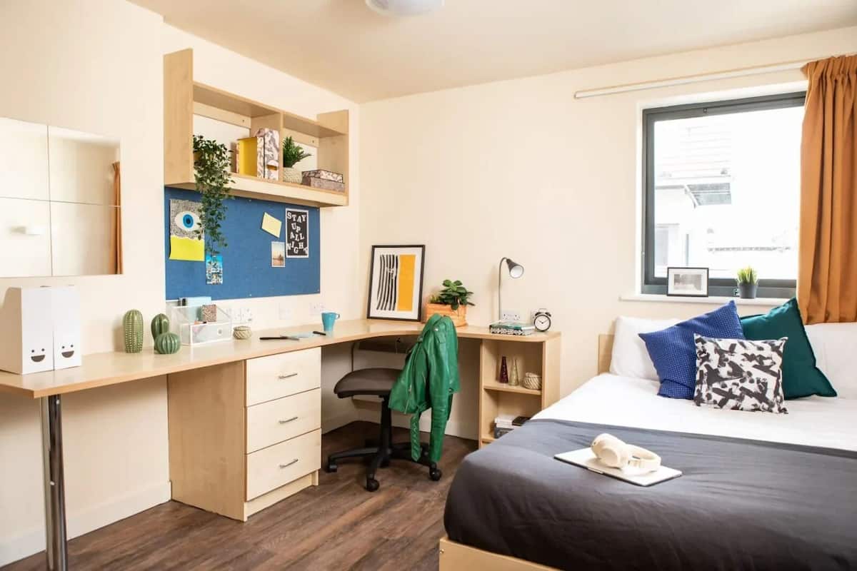 Une chambre moderne avec un bureau, un lit et une fenêtre avec des rideaux.