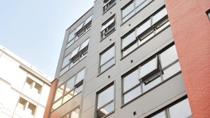 Un edificio de varios pisos con un diseño arquitectónico moderno, que combina fachadas de vidrio y ladrillo.