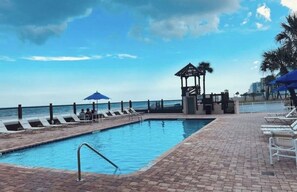 A pool area with lounge chairs and a gazebo overlooking the ocean. - Coastal Tides Ocean View Studio (Daytona Beach)