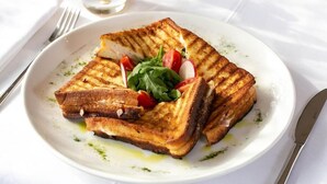 En tallerken med panini med tomat og rucola.