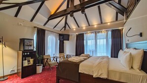 Et hotelværelse med en stor seng, et lille bord med stole, et fjernsyn og et minibar.