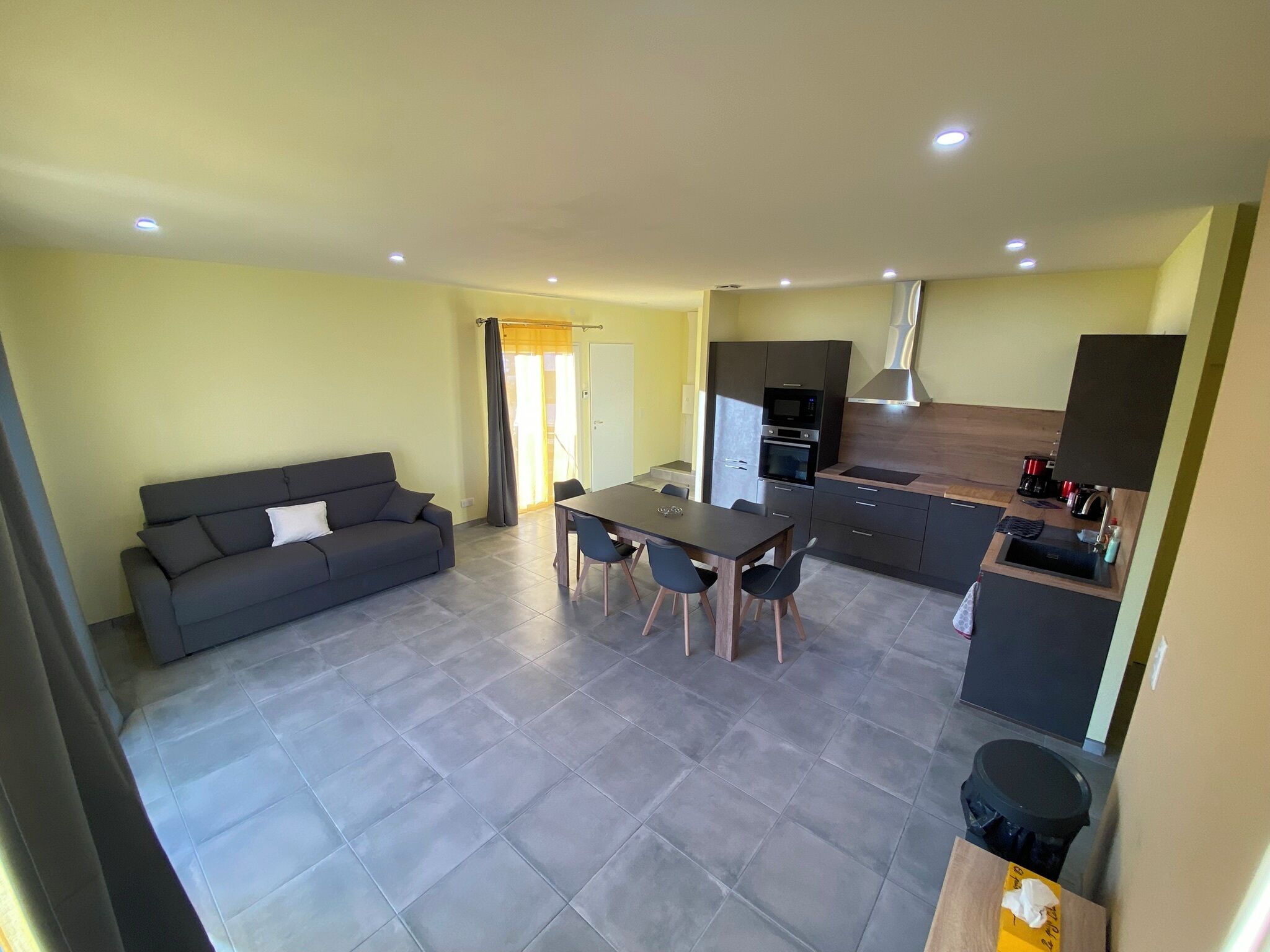 A modern apartment with a living area, dining space, kitchenette, and a small bathroom.