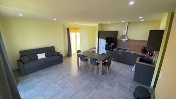 A modern apartment with a living area, dining space, kitchenette, and a small bathroom.