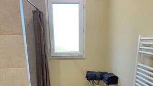 A bathroom with a shower, a window, a radiator, and a drying rack. - Charming bright apartment with large living room and 2 bedrooms - Comfort guaranteed (Trévillach)