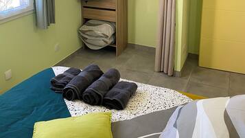 Un dormitorio con cama, armario, ventana con cortinas y puerta.