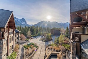 Un chalet doté d’une façade en pierre, de balcons en bois et offrant une vue sur des montagnes enneigées.