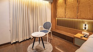 Een moderne hotelkamer met een groot raam, een wand met houten accenten, een ronde tafel en een stoel.