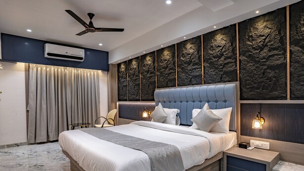 Een moderne slaapkamer met een groot bed, een plafondventilator, een airconditioning en een muur met een steenstructuur.