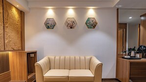 Een moderne hotellobby met een beige leren bank, houten lambrisering en zeshoekige wanddecoratie.