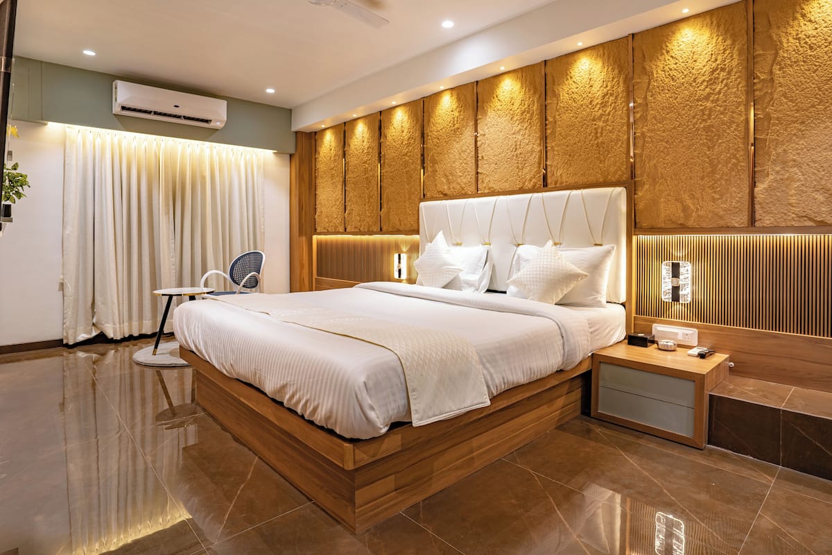 A modern bedroom with a wooden bed frame, a ceiling fan, an air conditioning unit, and a bedside table with a lamp.