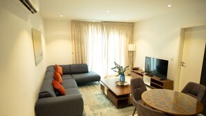 Una sala moderna con sofá, mesa de centro, televisor y un comedor con sillas.