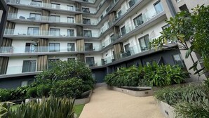 Un edificio residencial de varios pisos con balcones, un patio central con plantas y un diseño arquitectónico moderno.