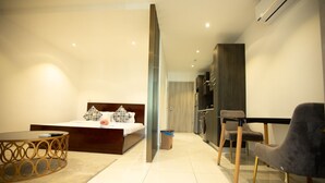 Habitación de hotel moderna con cama, una mesita redonda, una silla, kitchenette y baño.