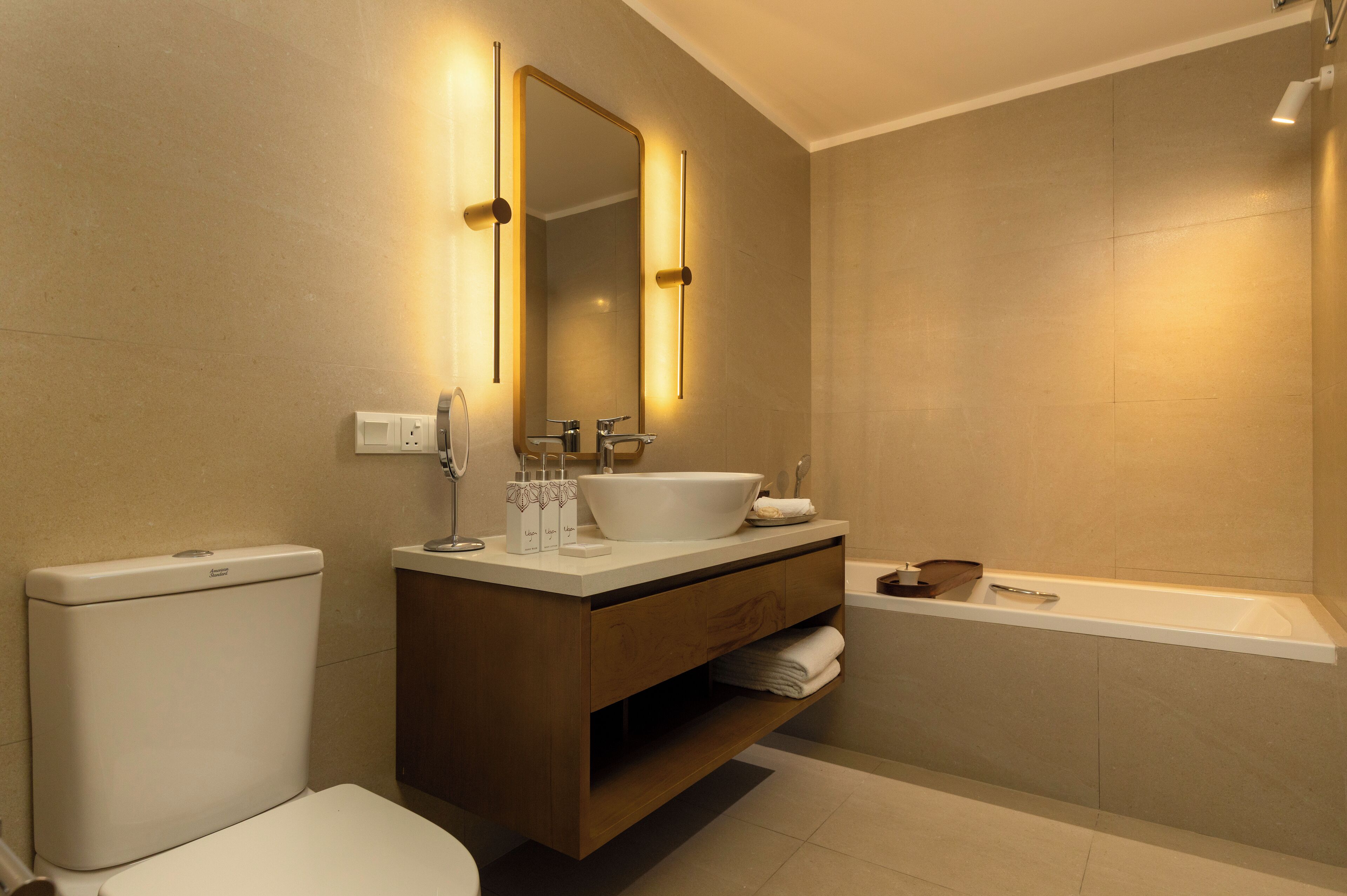 A modern bathroom with a large mirror, a white sink, and a bathtub.