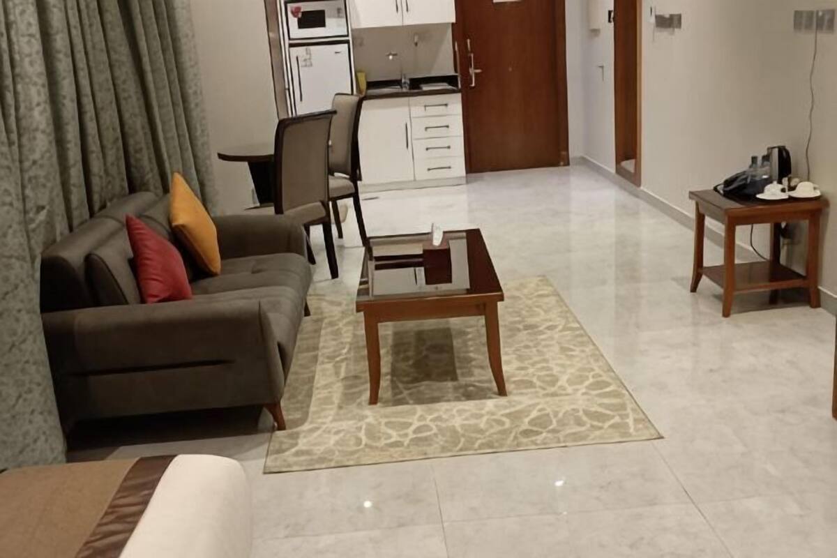 Een woonkamer met een bank, salontafel en een keuken op de achtergrond.