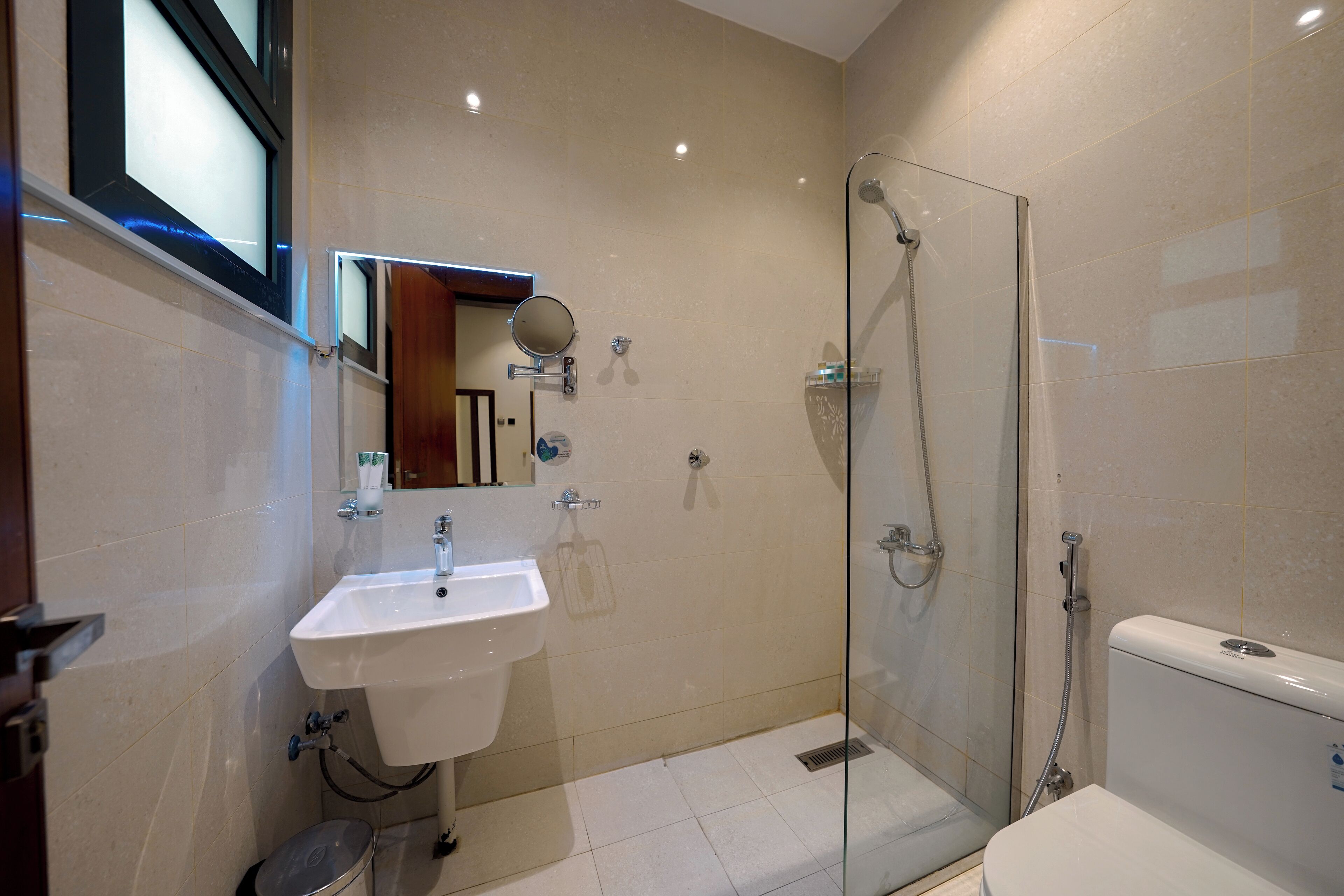 A modern bathroom with a glass-enclosed shower, a white sink, and a toilet.