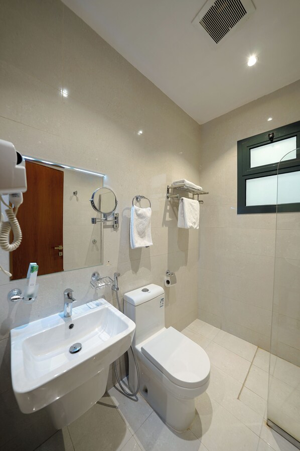Un baño moderno con lavamanos, espejo, inodoro y toallero.