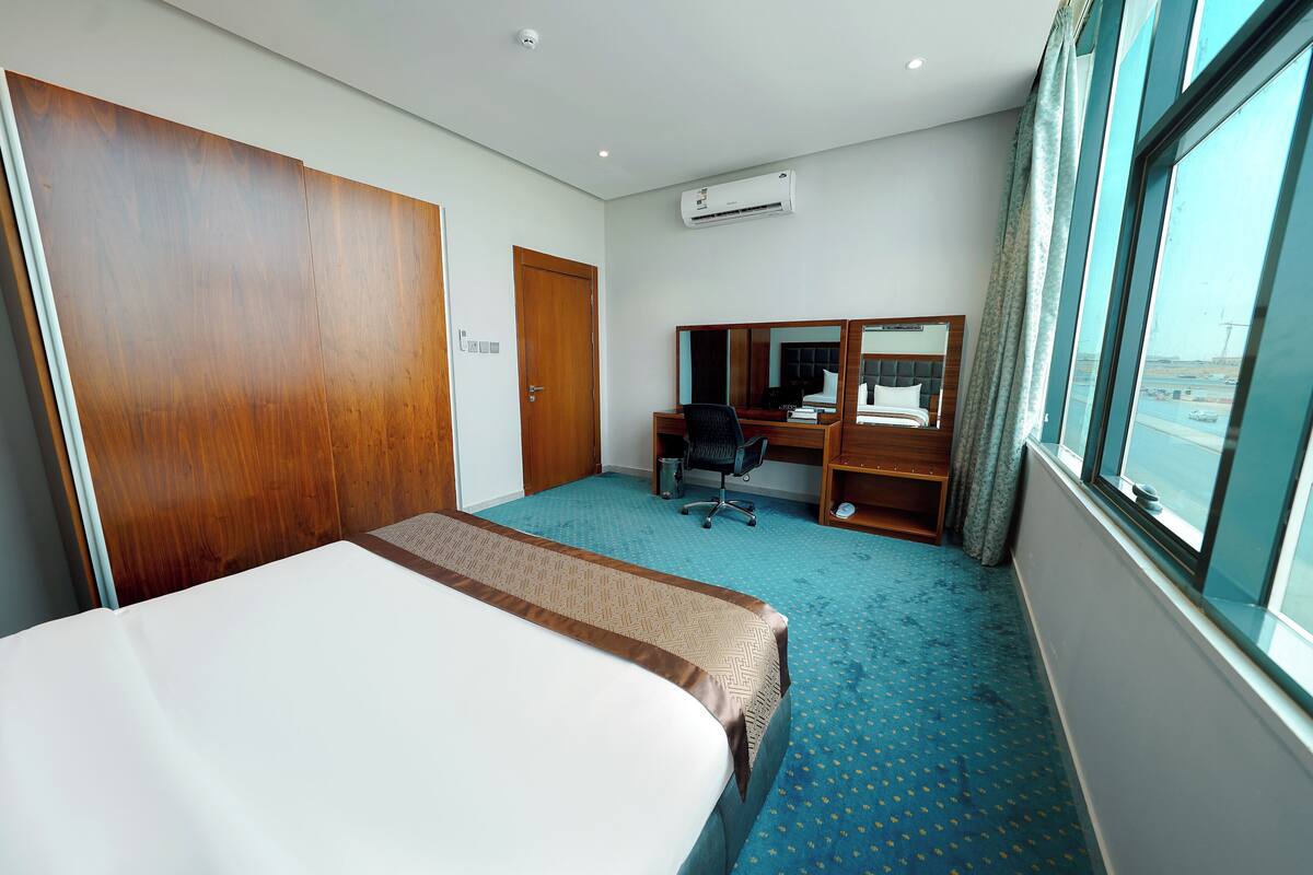 Een hotelkamer met een bed, een bureau, een stoel en een groot raam.