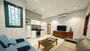A modern living room with a sofa, a coffee table, and a TV. - Celine Home Serviced apartment -Tuwaiq  (Riyadh)
