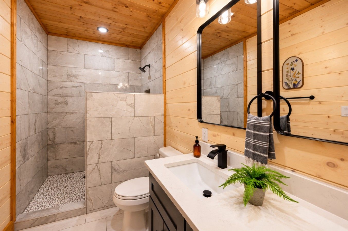 Ein modernes Badezimmer mit Dusche, Toilette und Waschbecken, ausgestattet mit Marmorfliesen und Holzakzenten.