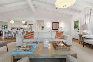 A spacious living room with a sofa, coffee table, and a dining area in the background. - LUX Private Modern Villa | Pool, Spa, & Dogs OK (Calistoga)