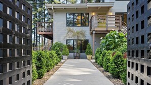 A modern building with a central pathway flanked by greenery, a balcony, and a staircase. - LUX Private Modern Villa | Pool, Spa, & Dogs OK (Calistoga)