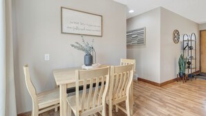 A dining area with a wooden table and chairs, a framed quote on the wall, and a potted plant. - The Modern Nest: Near Interstate, making it easy to get anywhere in Sioux Falls. (Sioux Falls)