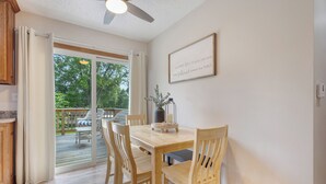 A dining area with a wooden table and chairs, a ceiling fan, and a view of the outdoors through a sliding glass door. - The Modern Nest: Near Interstate, making it easy to get anywhere in Sioux Falls. (Sioux Falls)