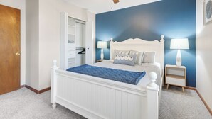 A bedroom with a white bed, a ceiling fan, and a blue accent wall. - The Modern Nest: Near Interstate, making it easy to get anywhere in Sioux Falls. (Sioux Falls)