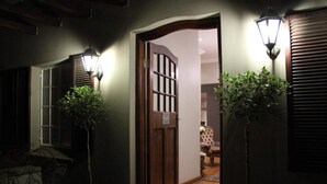 A hallway with a wooden door, potted plants, and a chair. - Abiénto Guesthouse (Bloemfontein)