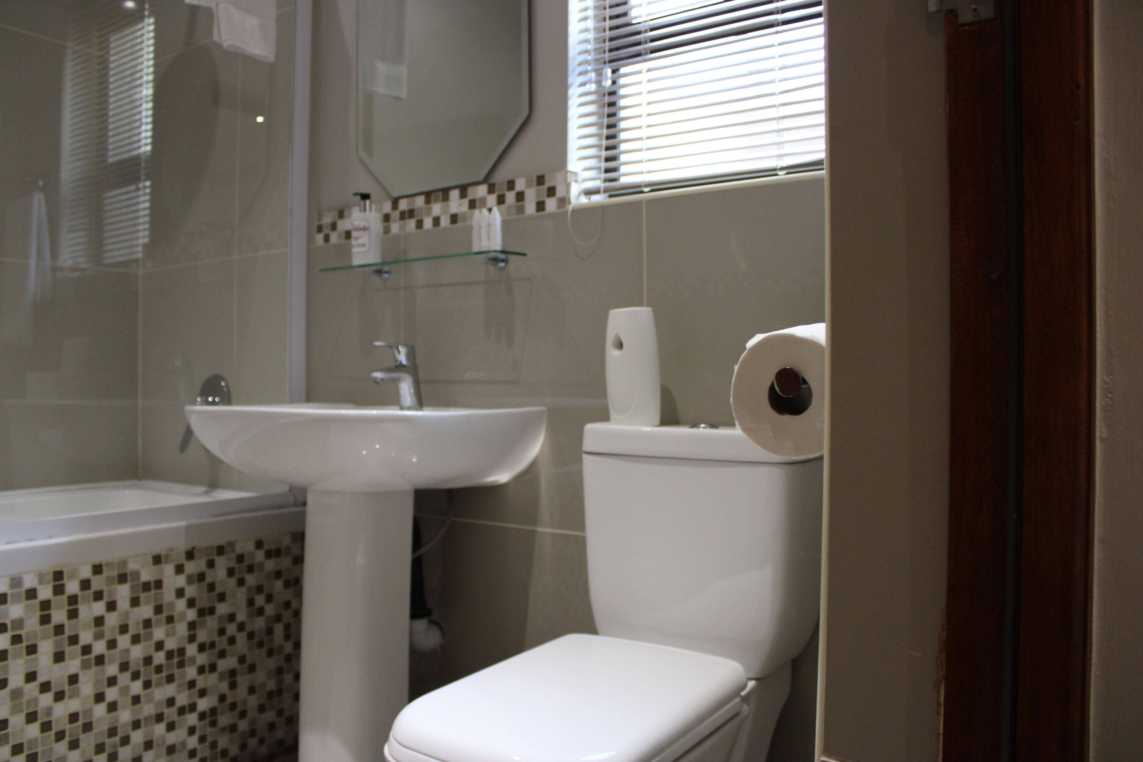 A bathroom with a white sink, toilet, and a glass shower enclosure.