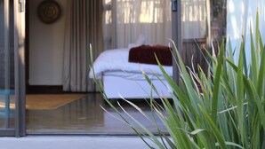 A bedroom with a bed, curtains, and a view of the outdoors. - Abiénto Guesthouse (Bloemfontein)