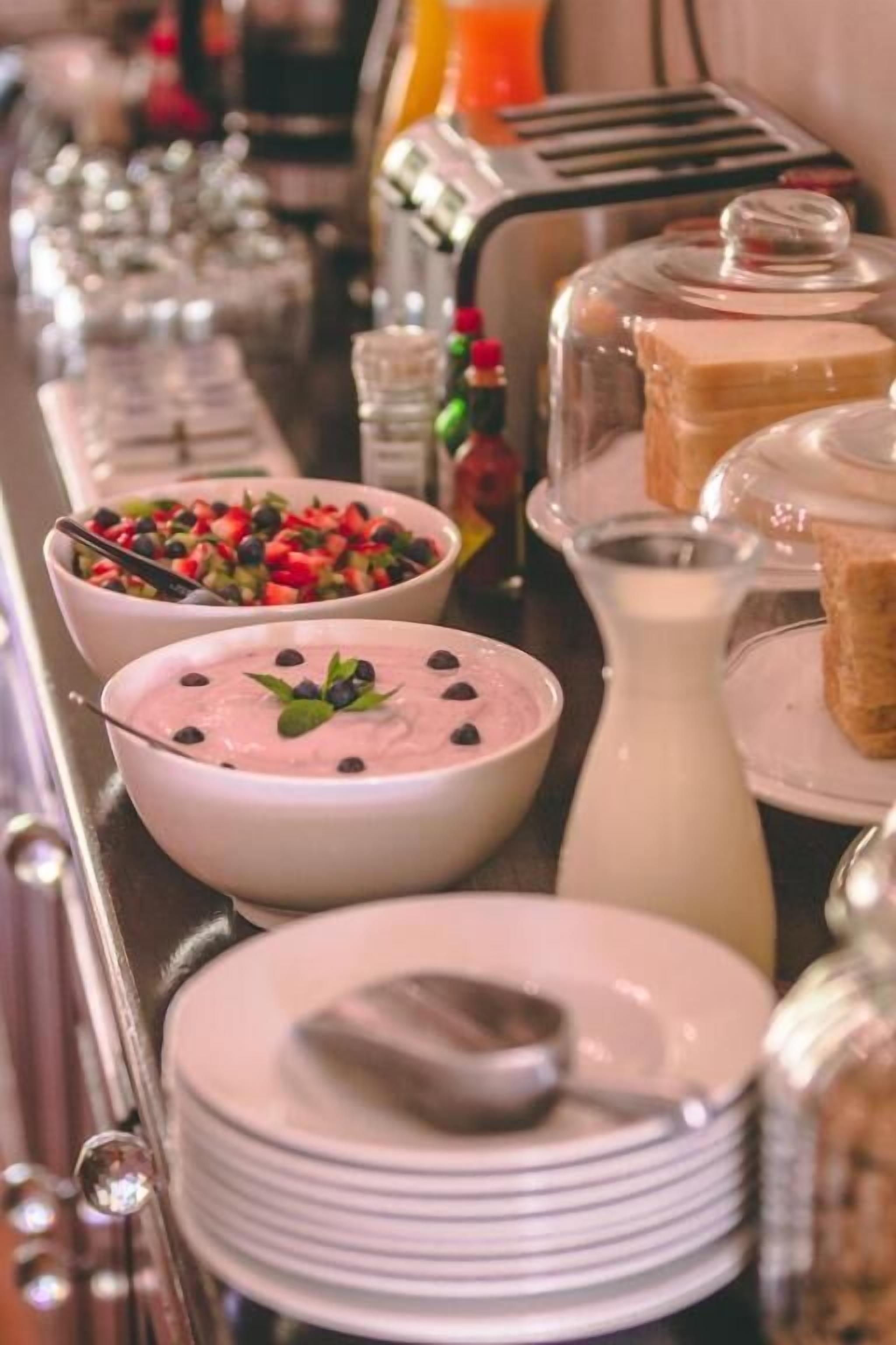 Ein reichhaltiges Buffet mit verschiedenen Speisen, darunter Schalen mit Joghurt und eine Kanne Milch.