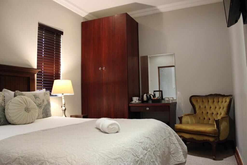 Habitació d'hotel amb un llit, un armari de fusta, un escriptori amb una cadira i un gran mirall.