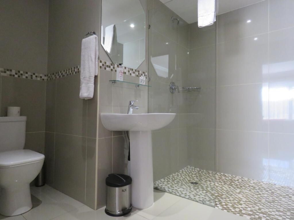 Ein modernes Badezimmer mit Toilette, Waschbecken und Duschbereich.