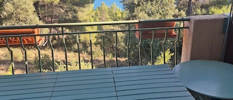 A balcony with a table and chairs, overlooking a body of water and trees.