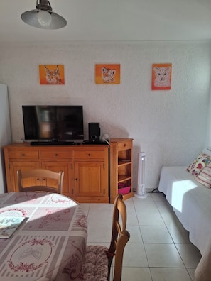 A room with a television, wooden cabinets, a bed, and wall art. - 8 Le Castellas (Sainte-Croix-du-Verdon)