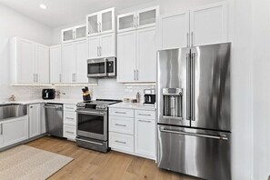 A modern kitchen with stainless steel appliances, white cabinetry, and a built-in microwave. - 30A | Rooftop Pool | Gulf Views | 2 Min To Beach! (Santa Rosa Beach)