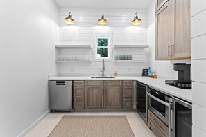 A modern kitchen with white cabinetry, a built-in dishwasher, and a coffee machine. - 30A | Rooftop Pool | Gulf Views | 2 Min To Beach! (Santa Rosa Beach)