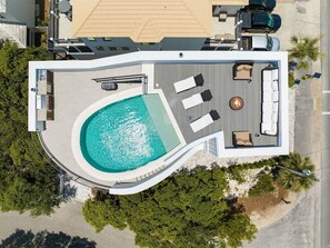 A modern hotel with a rooftop pool, lounge area, and a fire pit.