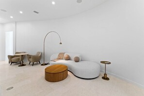 A modern living room with a curved sofa, two armchairs, a coffee table, and a floor lamp.