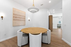A modern dining area with a round wooden table, cushioned chairs, and a pendant light. - 30A | Rooftop Pool | Gulf Views | 2 Min To Beach! (Santa Rosa Beach)