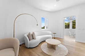 A modern living room with a curved sofa, a round coffee table, and a floor lamp. - 30A | Rooftop Pool | Gulf Views | 2 Min To Beach! (Santa Rosa Beach)
