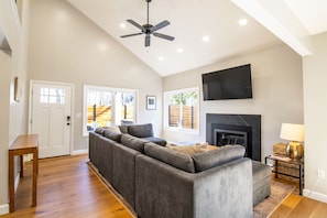 A living room with a sectional sofa, a fireplace, a ceiling fan, and a television mounted on the wall. - Close to Adventure Park, Hot tub, Dog friendly! (Massanutten)