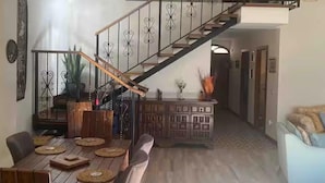 Ein Essbereich mit Holztisch und Stühlen, eine Treppe mit dekorativer Geländer und eine Küchenzeile mit Schränken und Arbeitsplatte.