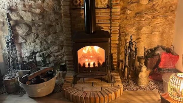 Ein Steinkamin mit Feuer, eine Holzschale und ein Laternen auf dem Boden.