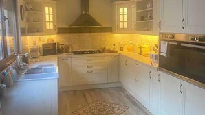 Eine moderne Küche mit weißen Schränken, einem Gasherd, einem Backofen und einem großen Fenster.