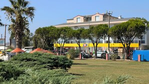 Ein Gebäude mit gelber Fassade, umgeben von Bäumen und parkenden Autos.