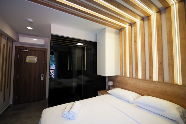 Ein Hotelzimmer mit einem Bett, einem hölzernen Kopfteil, einem Nachttisch und einem Spiegel.