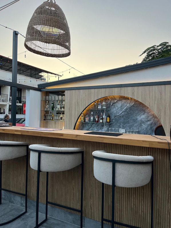 A bar area with a wooden counter, bar stools, and a marble backsplash.